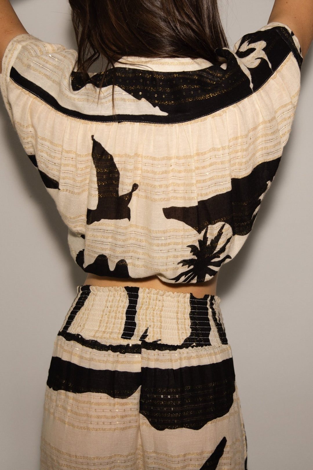 Person wearing a black and white patterned outfit against a neutral background