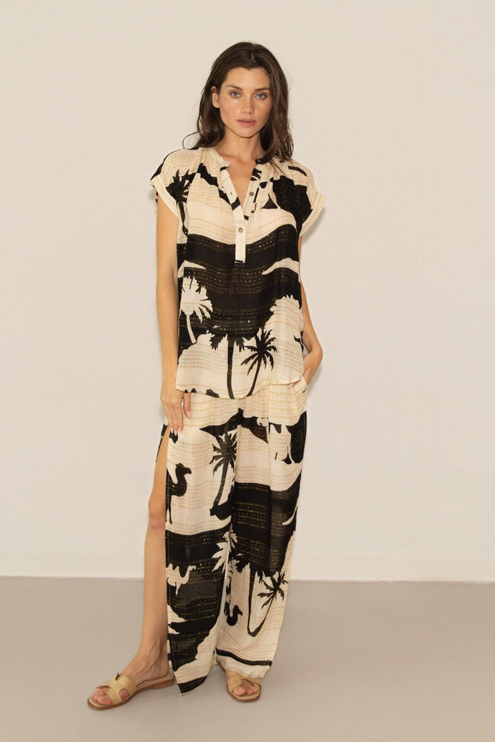 Woman wearing a black and white palm tree patterned outfit on a plain background