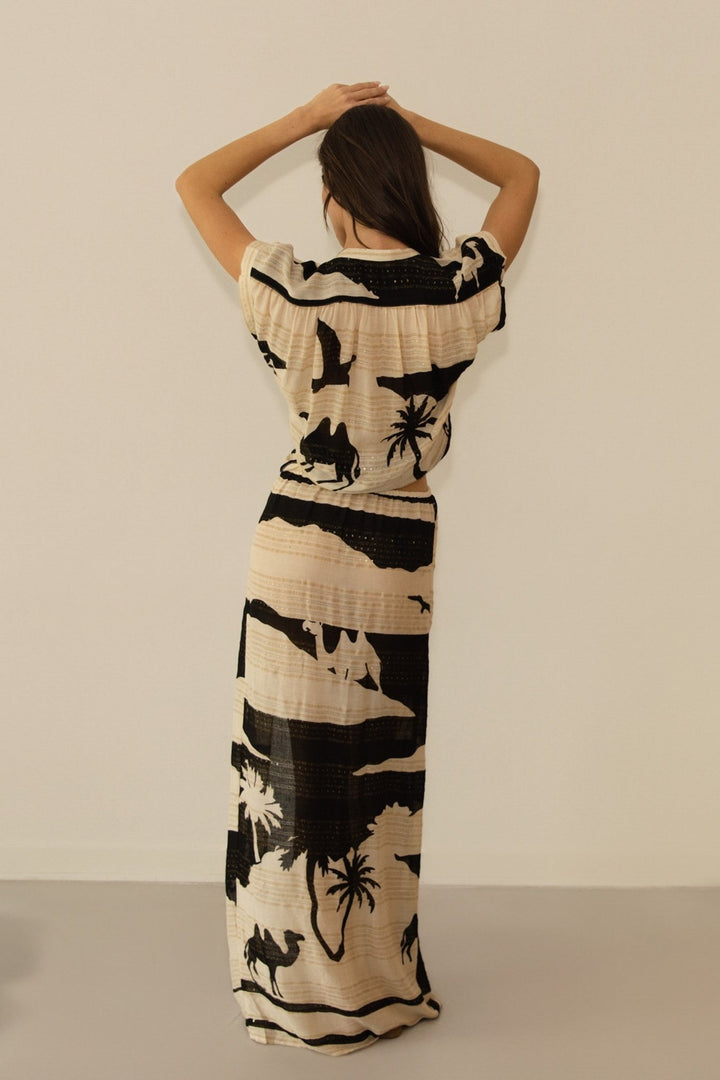 Woman wearing a long dress with black abstract patterns on a beige background