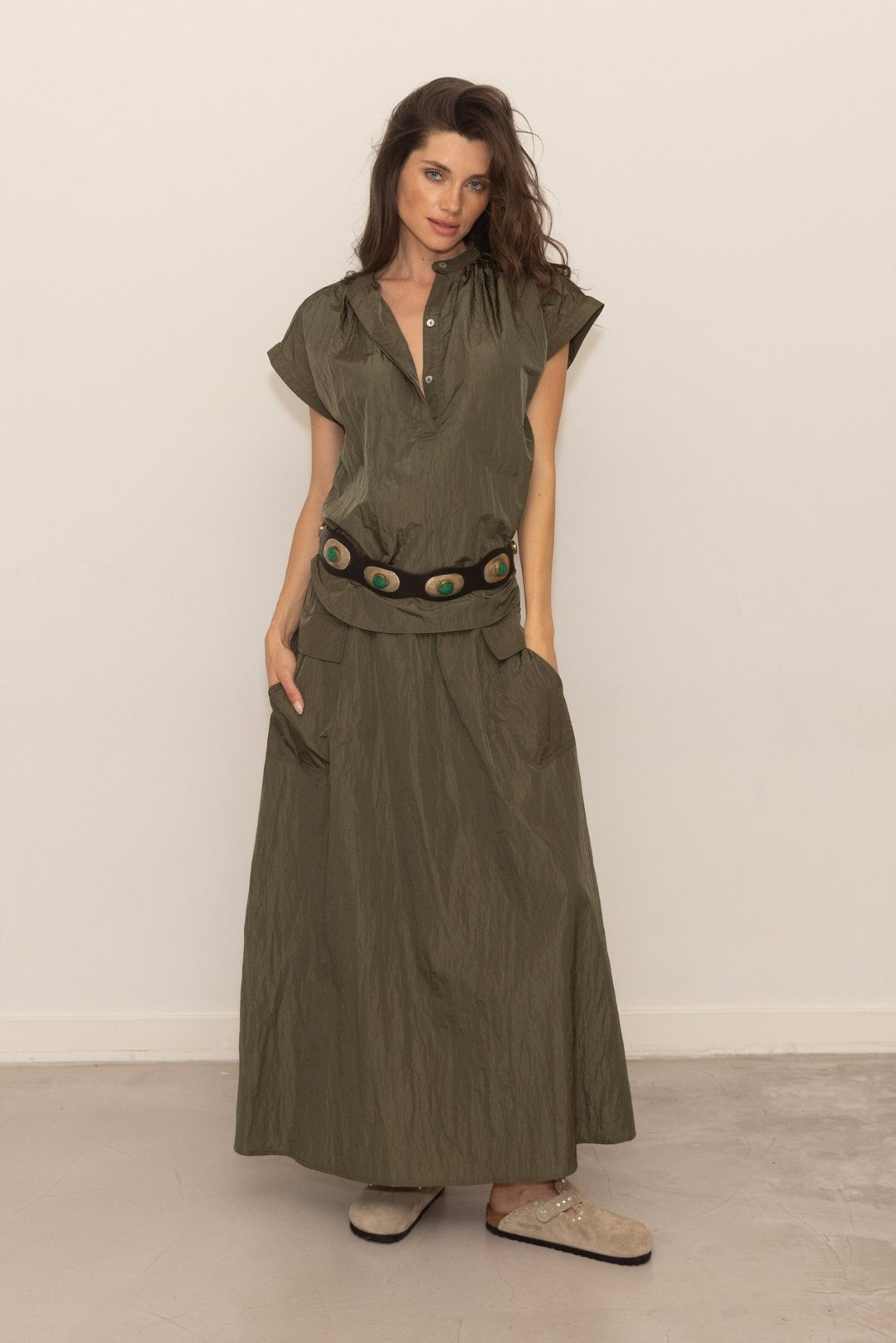 Woman wearing a green outfit with a belt against a white background