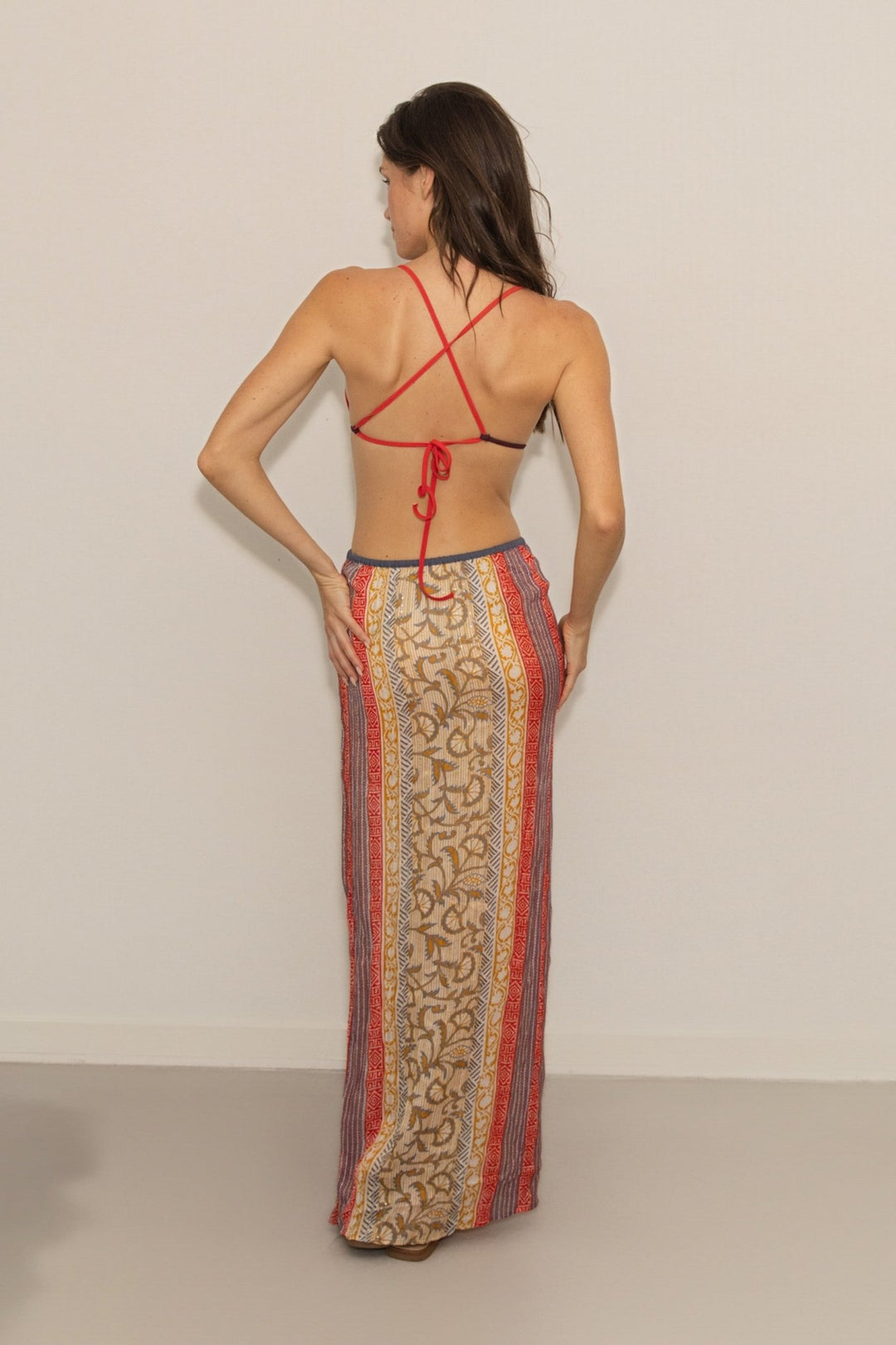 Woman wearing a patterned dress with a red top and beige background