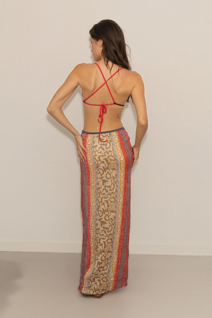 Woman wearing a patterned dress with a red top and beige background