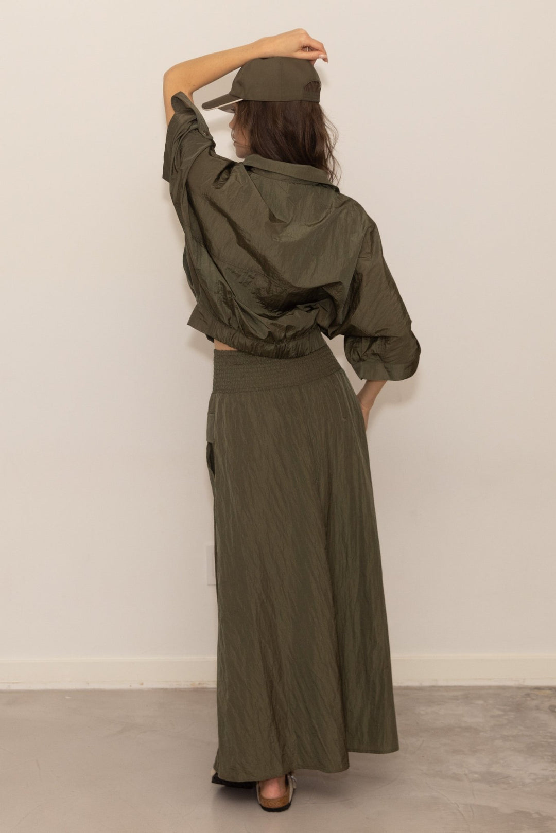 Person wearing a green outfit with a matching cap against a plain background