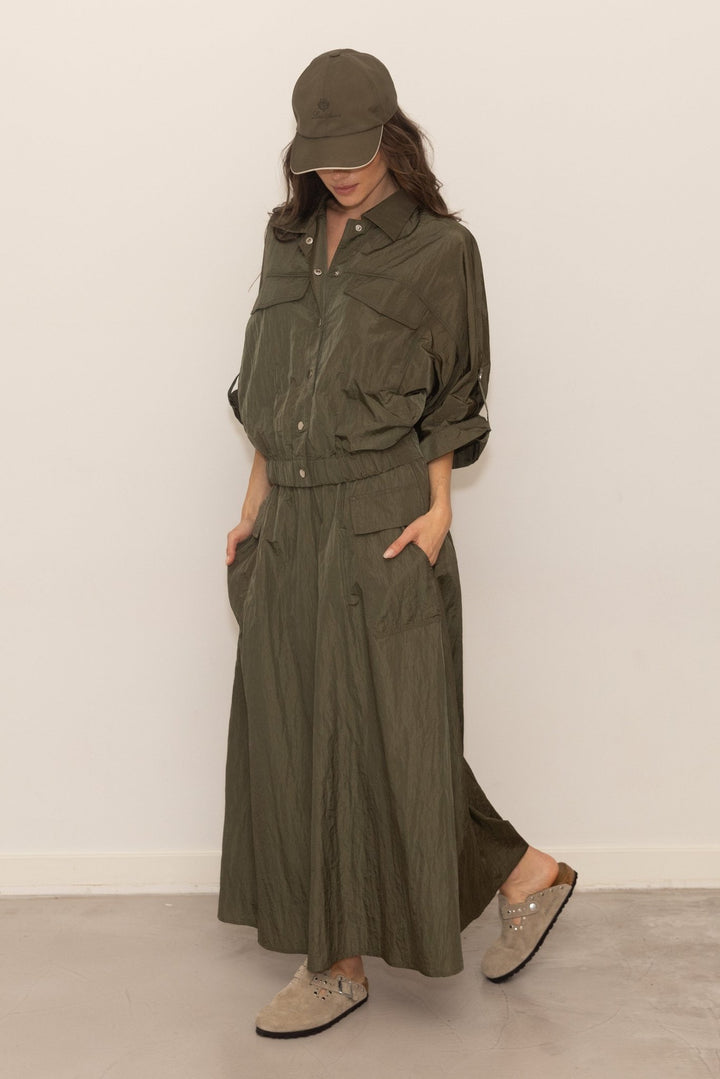 Person wearing an olive green outfit with a matching cap against a white background