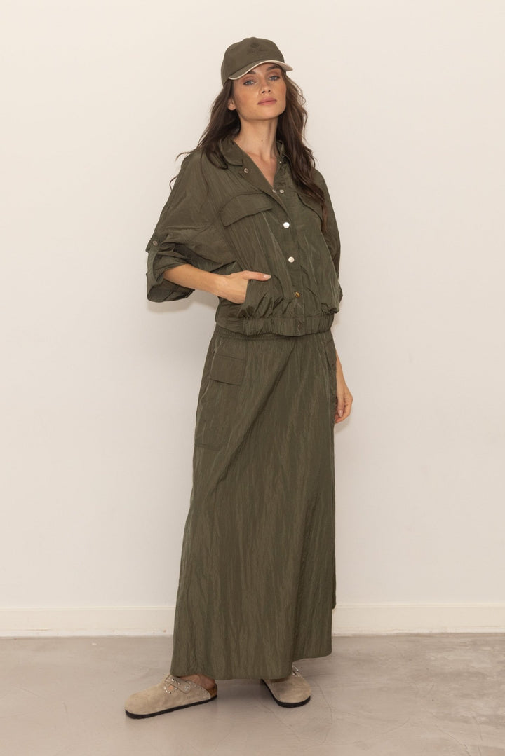 Woman wearing a green jumpsuit and cap against a white background