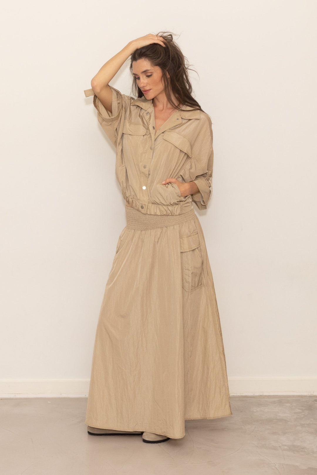 Woman wearing a beige trench coat against a white background