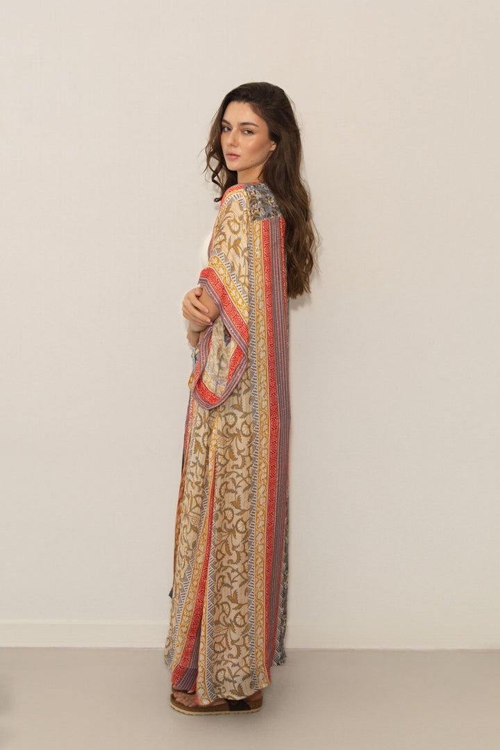 Woman wearing a long, patterned dress with a neutral background