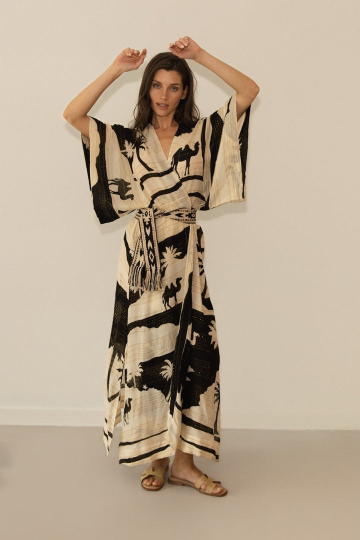 Woman wearing a black and beige patterned dress against a plain background