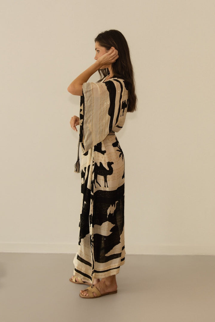 Woman wearing a black and beige patterned outfit against a plain background