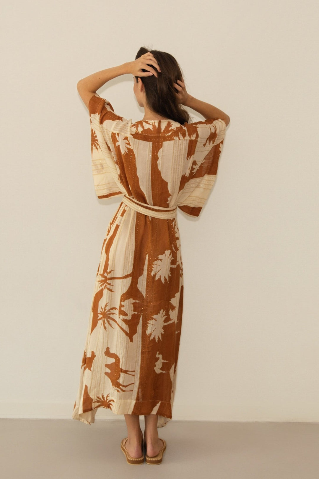Woman wearing a long, patterned dress against a plain background