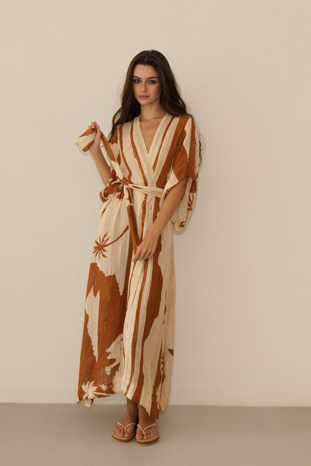 Woman wearing a long, patterned dress against a plain background