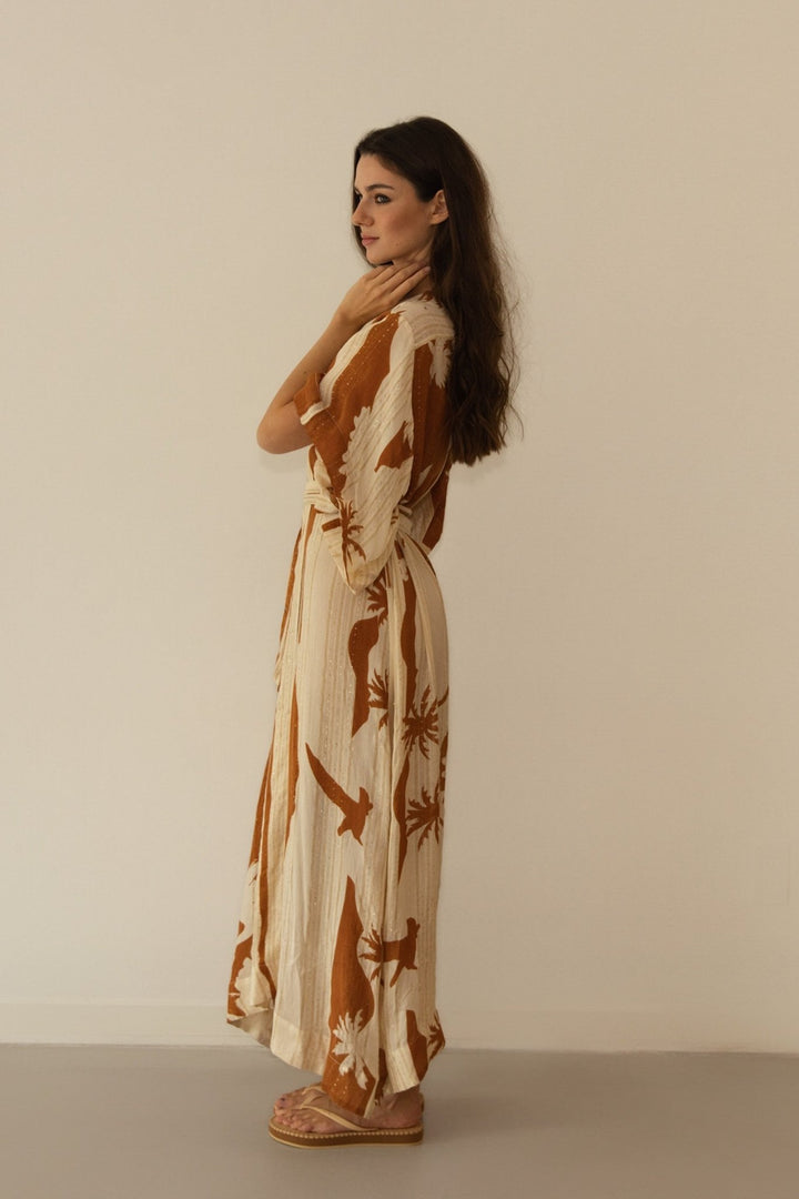 Woman wearing a long, patterned dress against a plain background