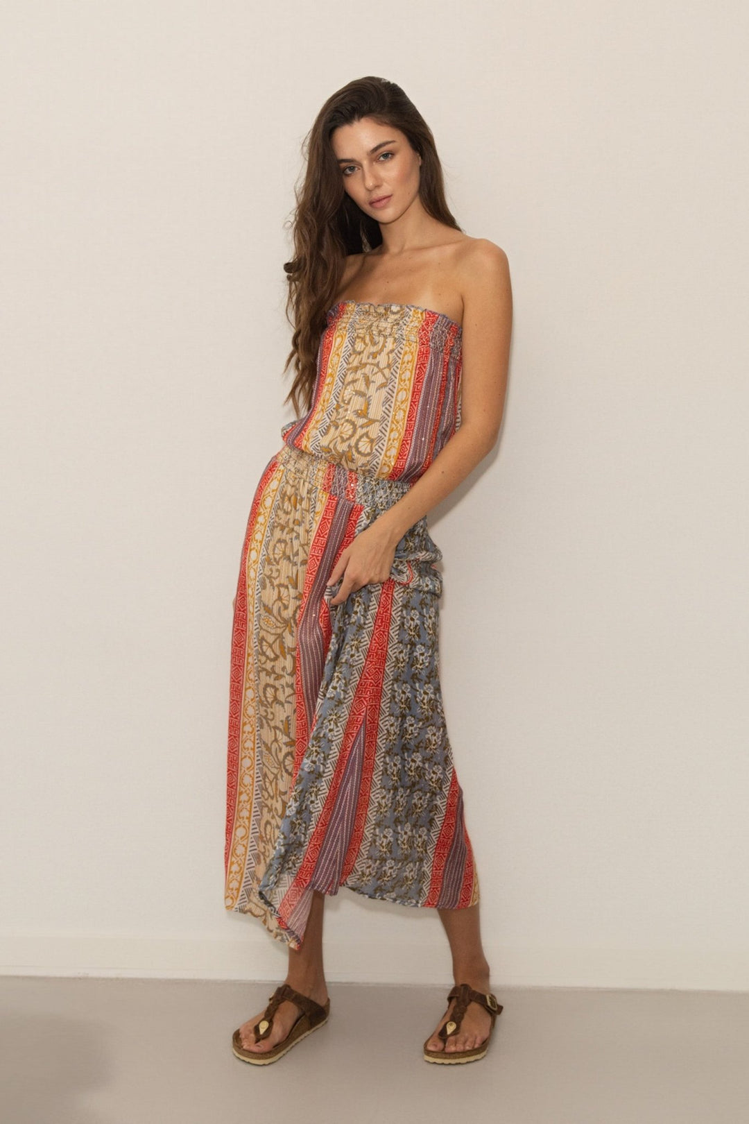 Woman wearing a strapless dress with a colorful pattern on a plain background