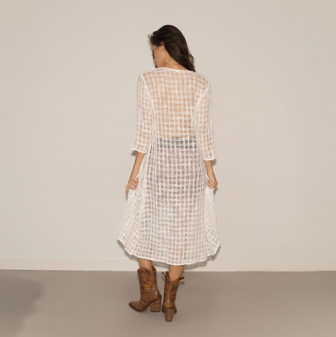 Woman wearing a checkered dress and brown boots against a plain background