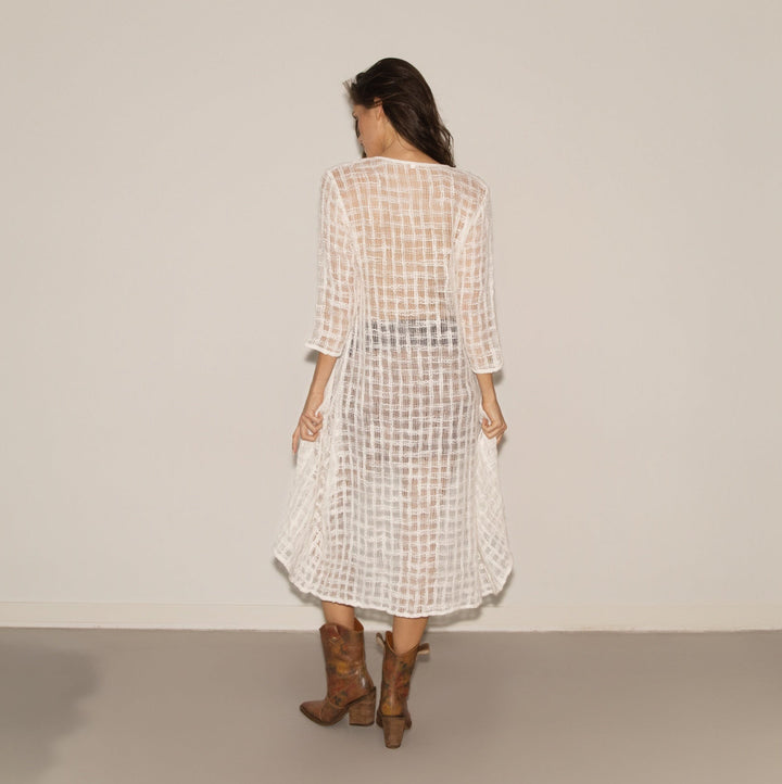 Woman wearing a checkered dress and brown boots against a plain background