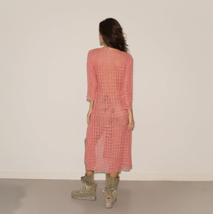 Woman wearing a pink checkered dress with a plain background