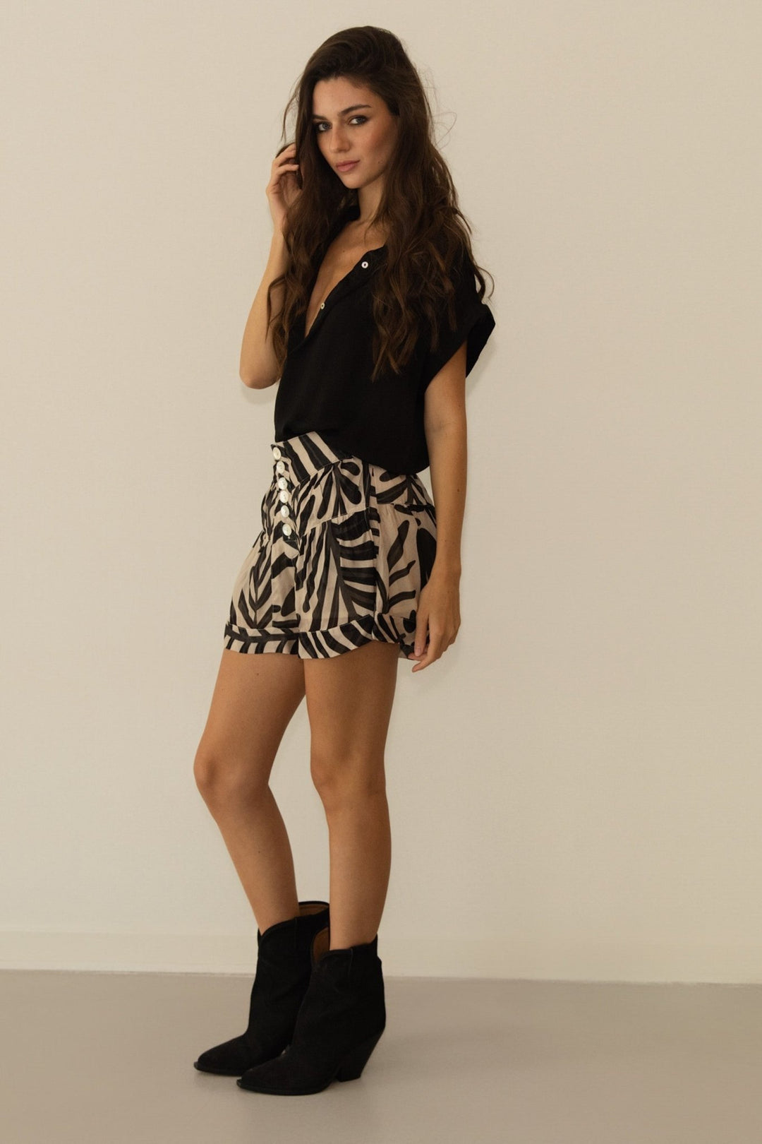 Woman wearing a black top and zebra print skirt against a plain background