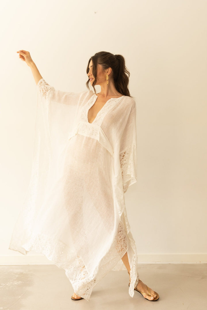 Woman wearing a white lace dress against a plain background