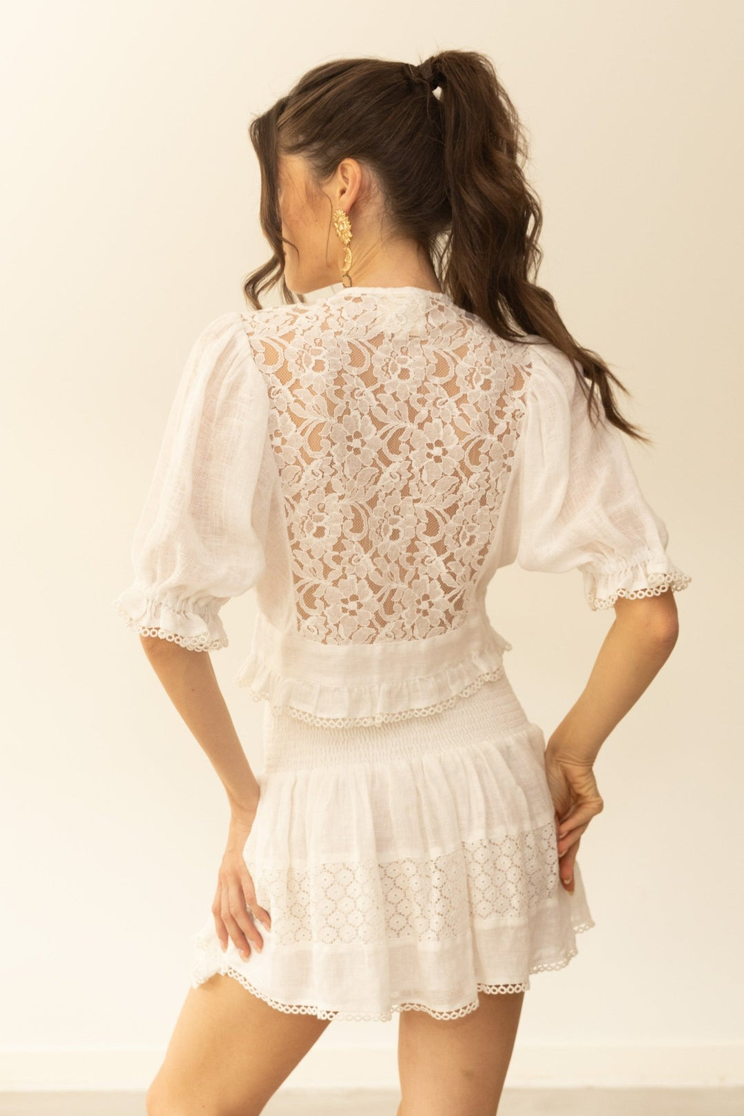 Woman wearing a white lace dress against a plain background