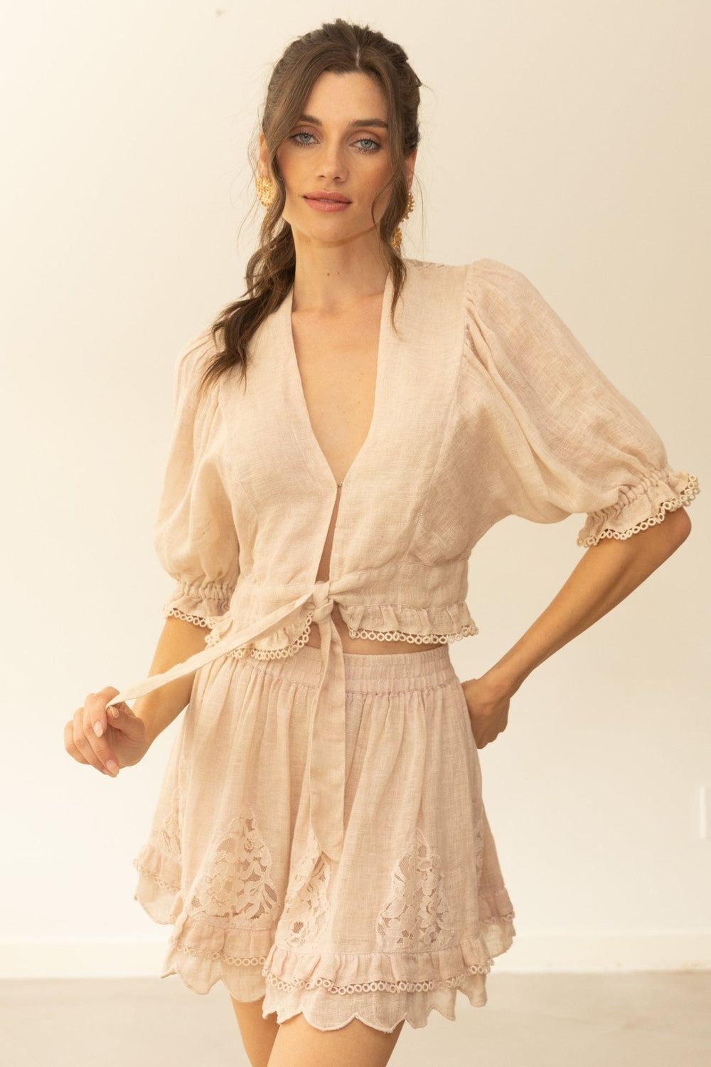 Woman wearing a beige lace outfit against a plain background