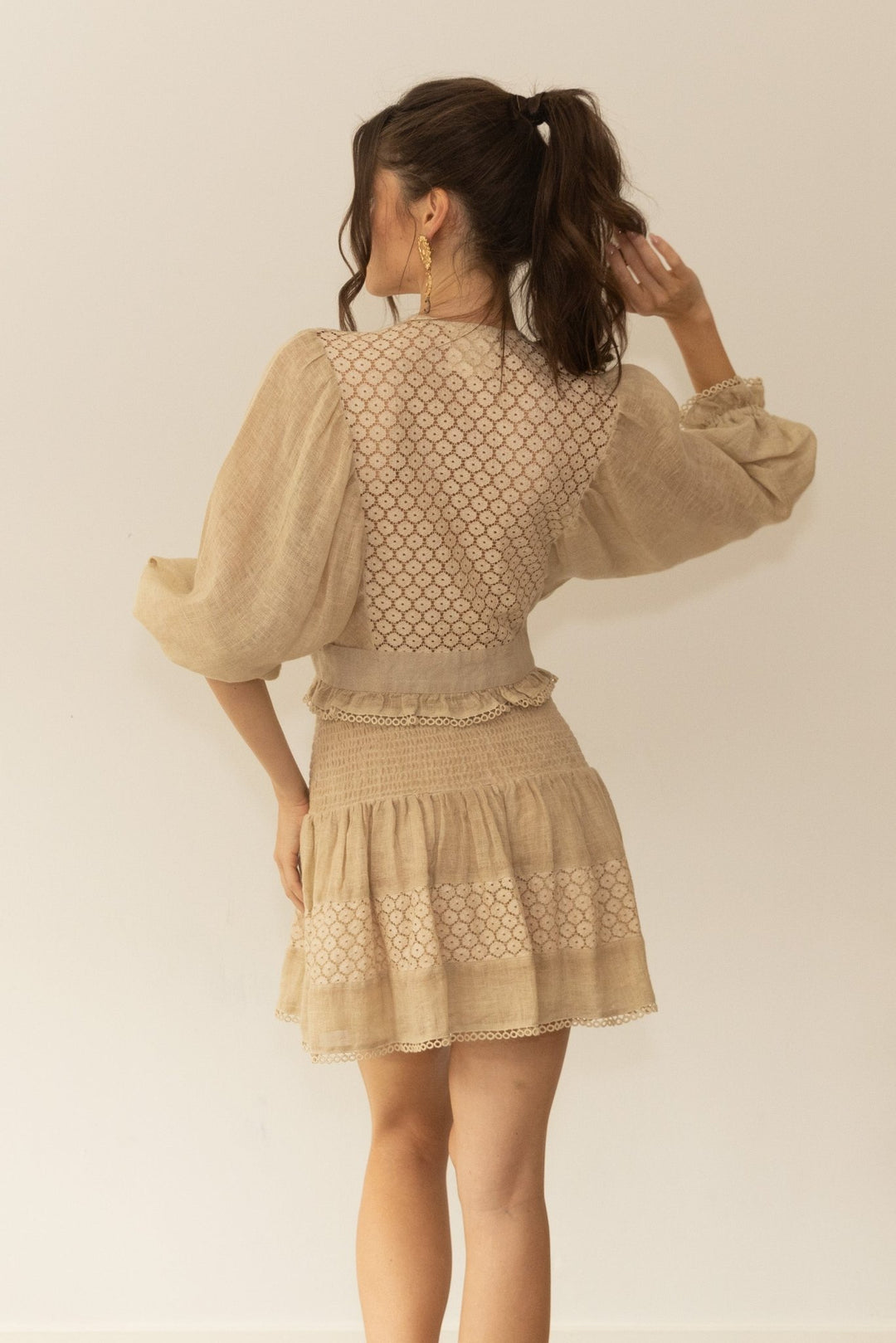 Woman wearing a beige dress with lace details against a plain background
