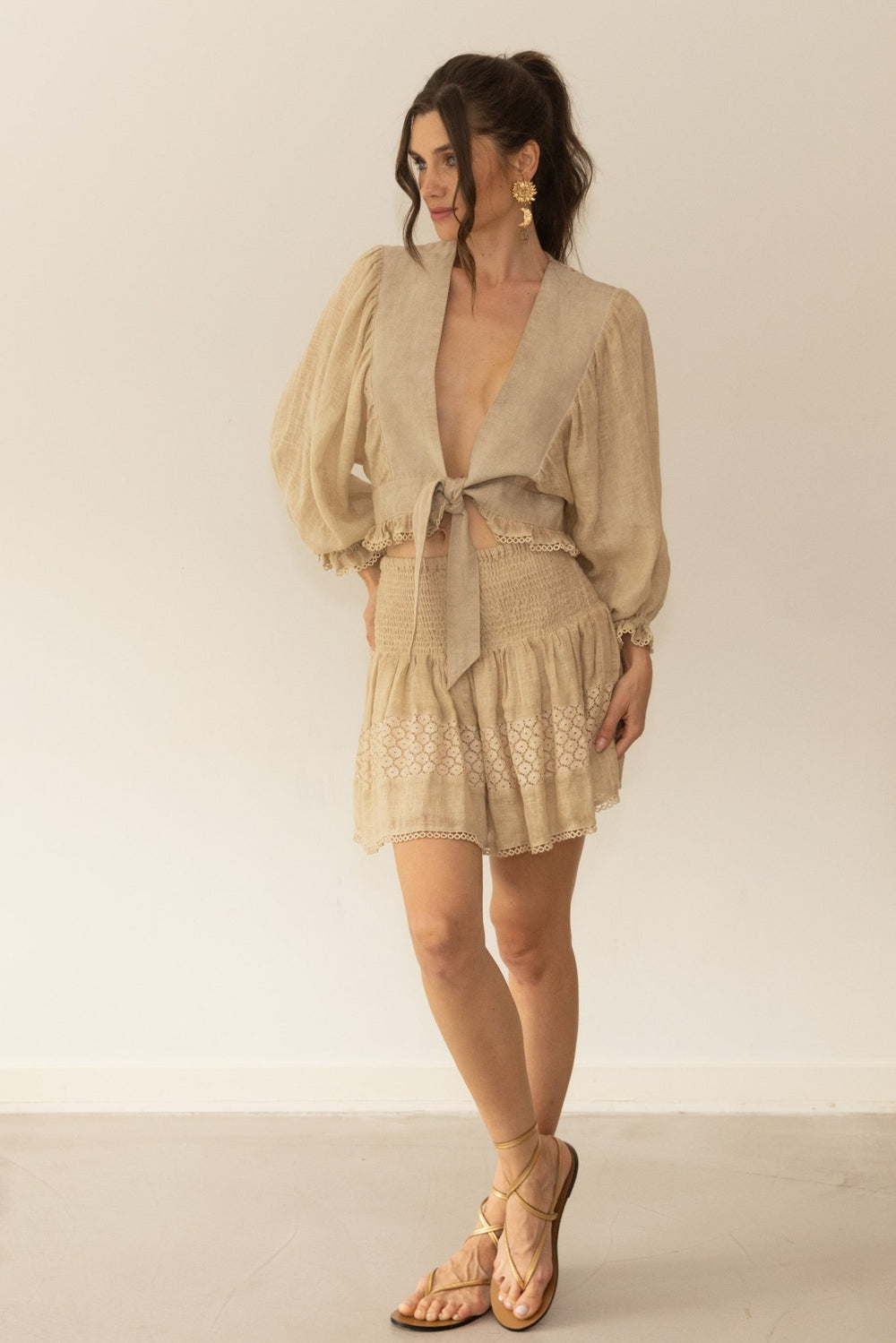 Woman wearing a beige dress with a matching jacket against a plain background