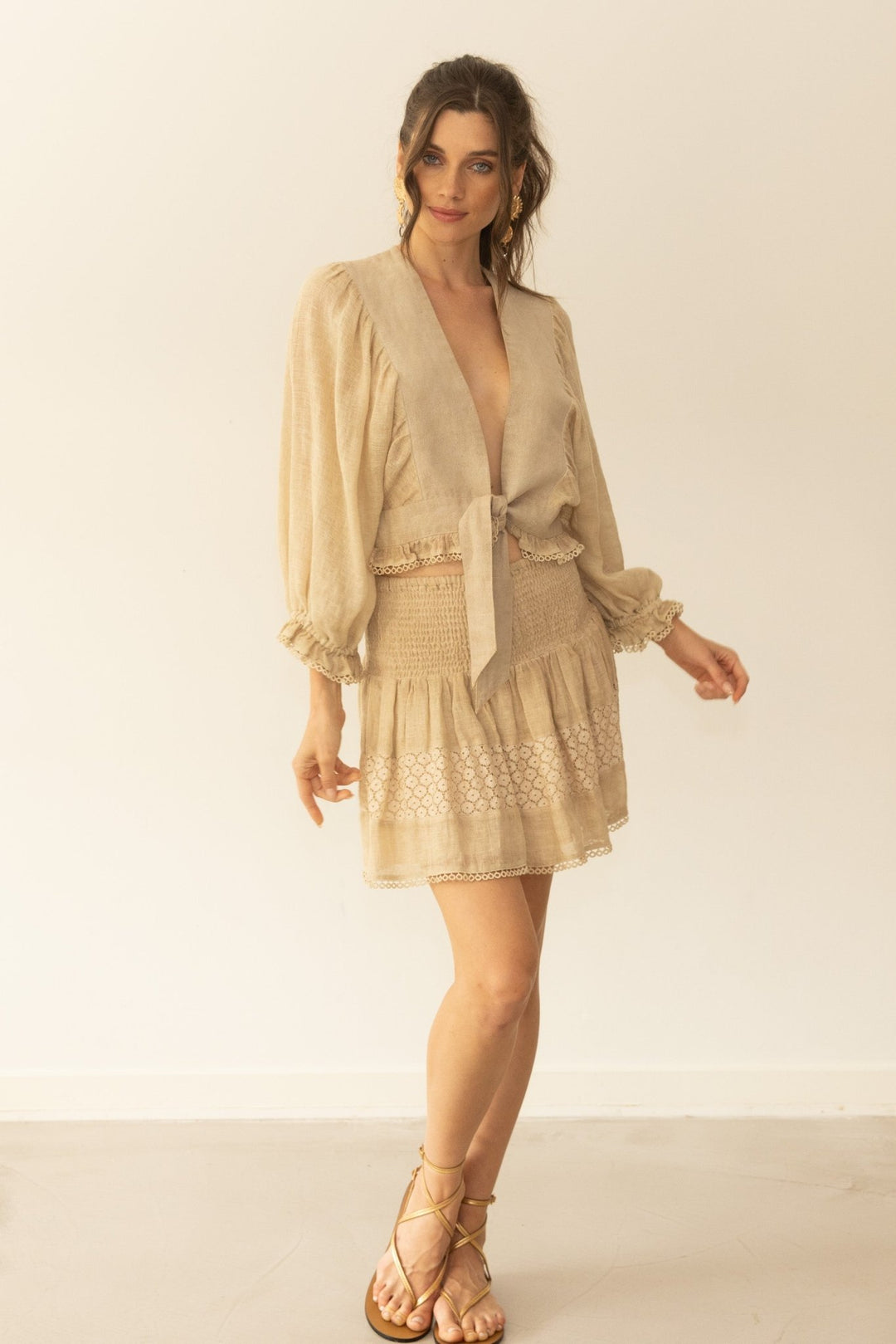 Woman wearing a beige dress with a matching jacket against a white background
