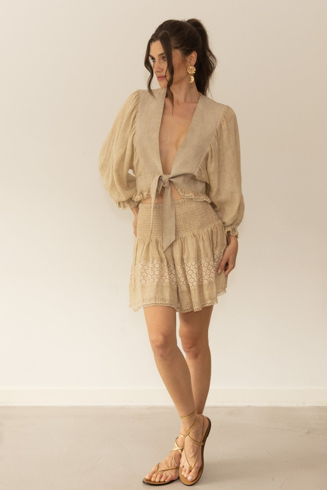 Woman wearing a beige dress with a matching jacket against a plain background