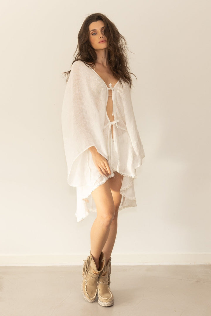 Woman wearing a white dress with beige boots against a plain background