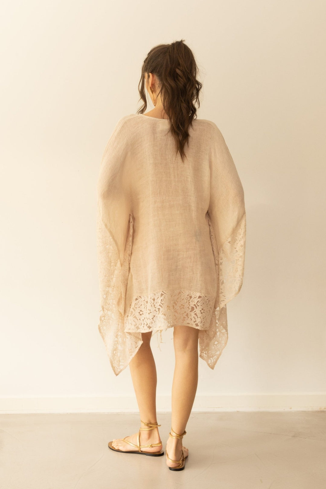 Woman wearing a beige lace dress against a plain background