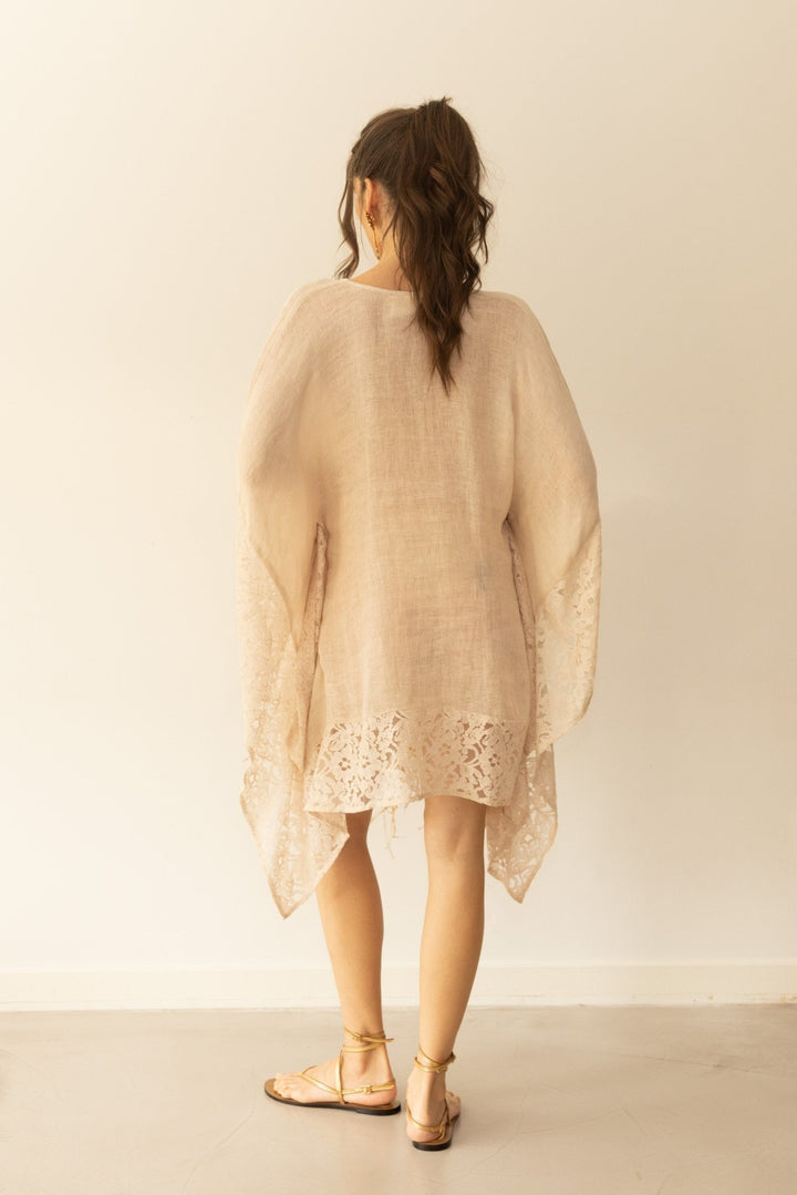 Woman wearing a beige lace dress against a plain background