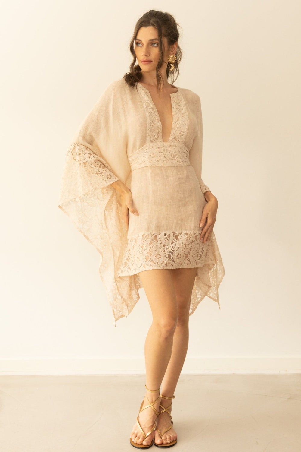 Woman wearing a beige lace dress with a plain background