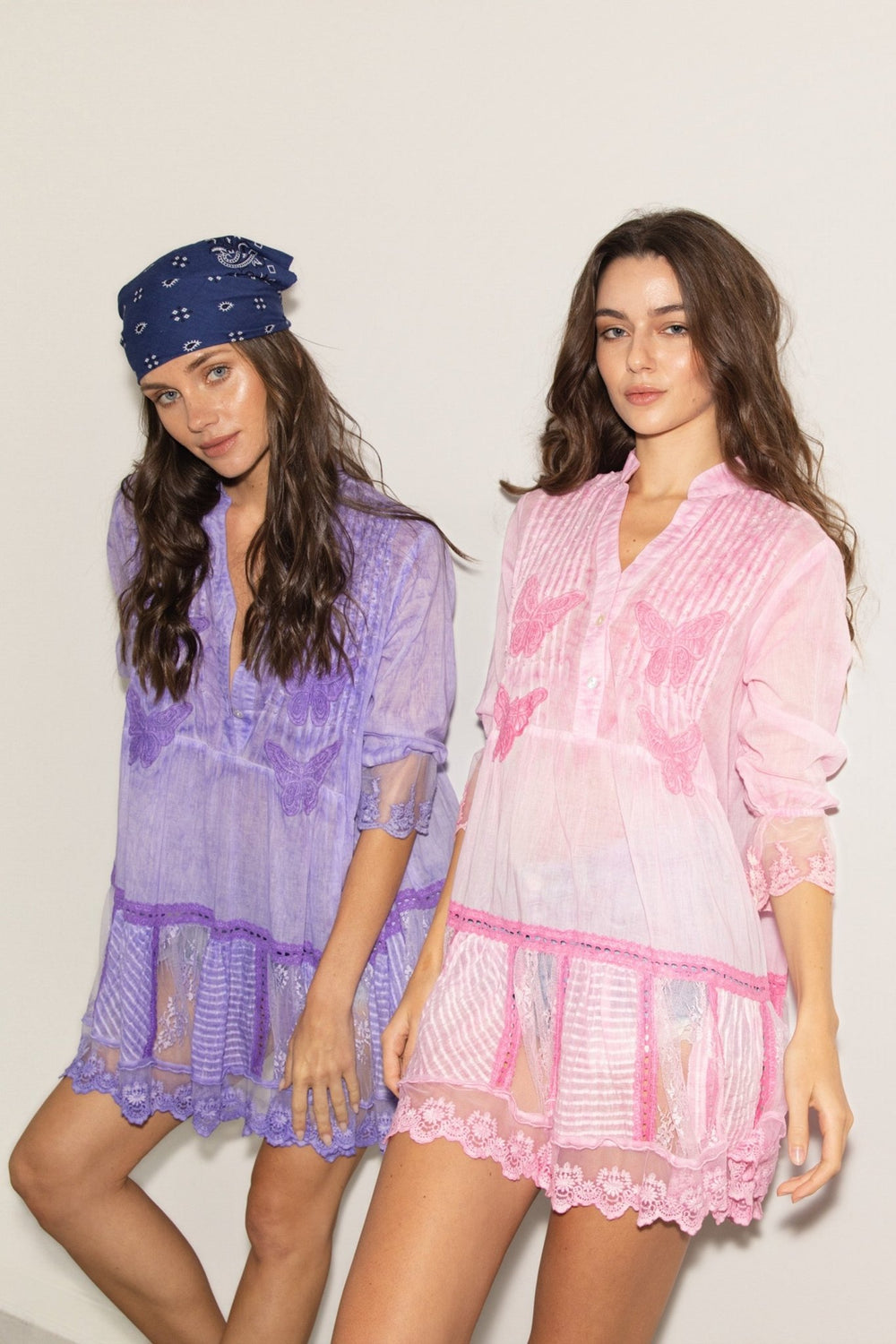 Two women wearing colorful lace cover-ups against a plain background