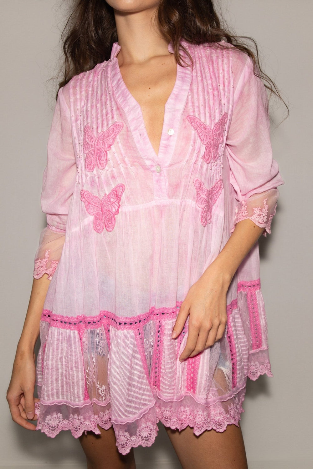 Pink lace dress with butterfly patterns on a plain background